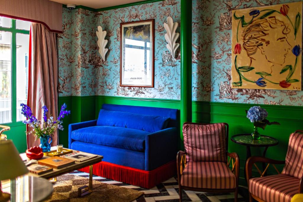 een woonkamer met een blauwe bank en groene muren bij Hôtel Les Deux Gares in Parijs