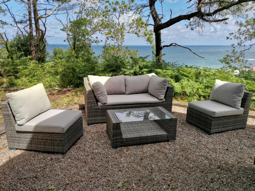 3 sillas de mimbre y una mesa de centro en un patio en Au courtil des chênes marins, meublé 3 étoiles en Digosville