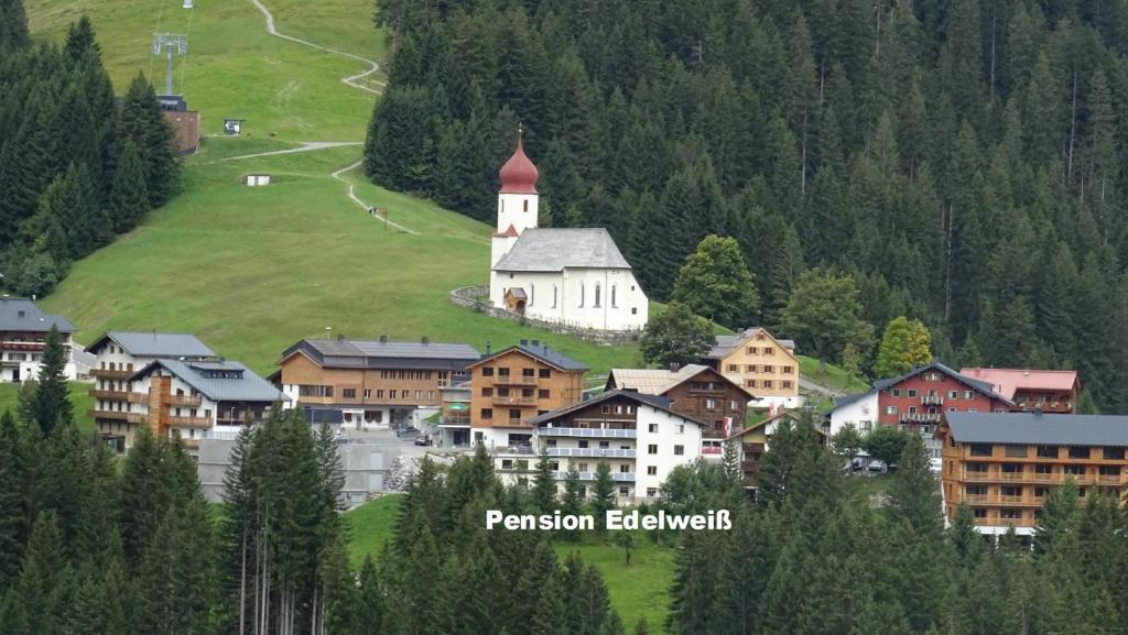 una piccola città con una chiesa in mezzo a una montagna di Pension Edelweiss a Damuls