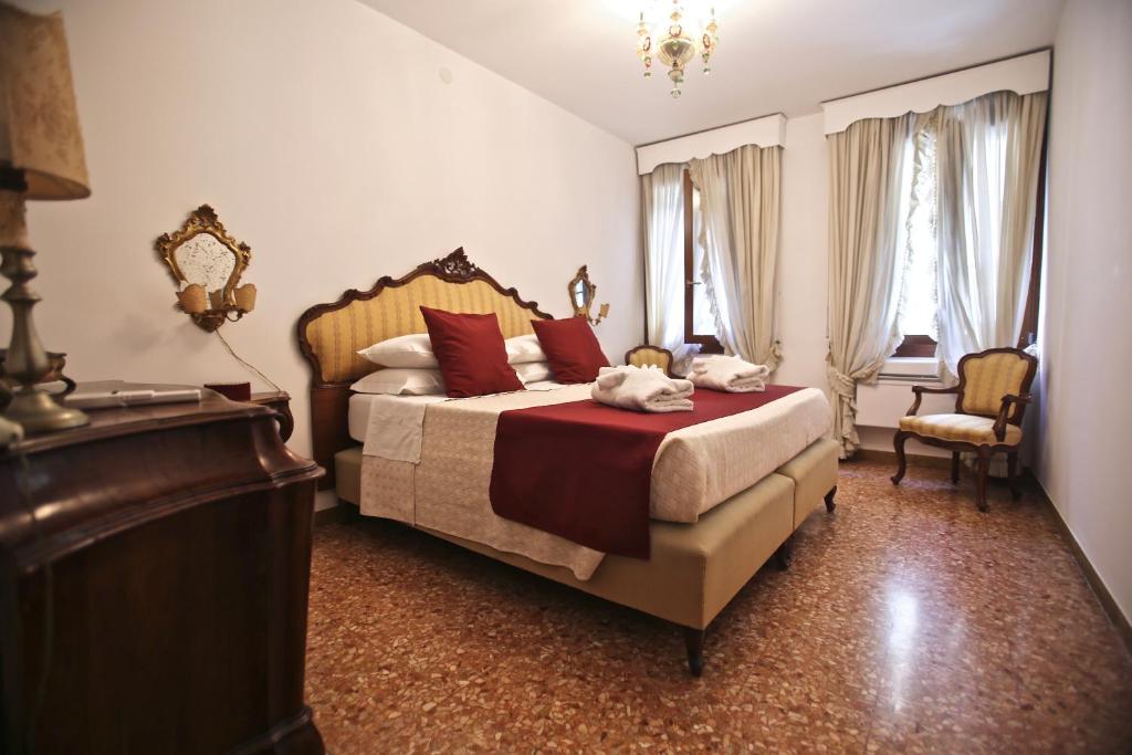 威尼斯的住宿－Ca Donzela，一间卧室配有一张带红色枕头的床和梳妆台