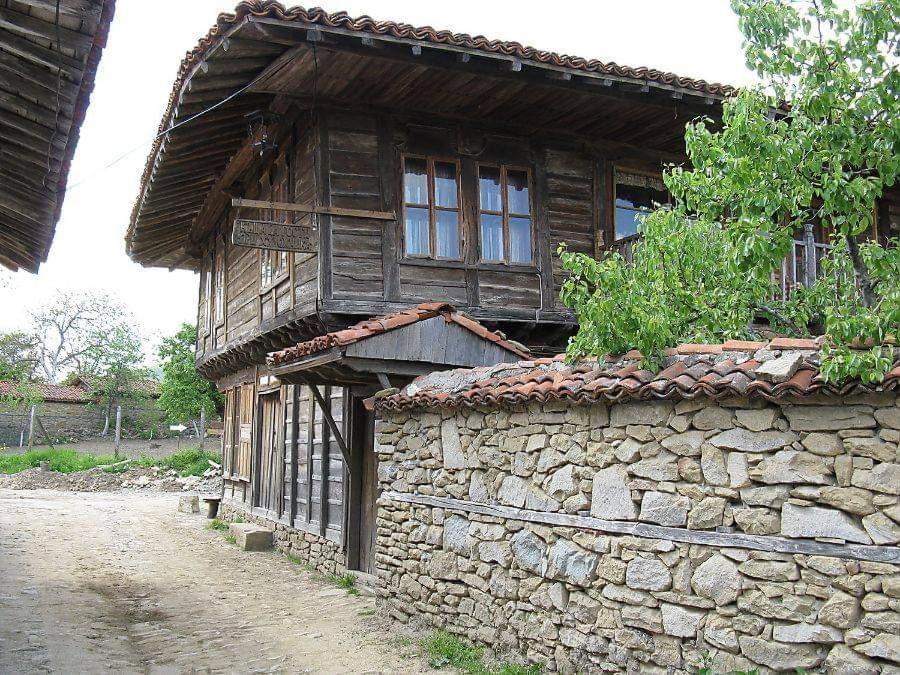 - un vieux bâtiment en pierre avec des fenêtres donnant sur une rue dans l'établissement Къщата на художника, à Zheravna