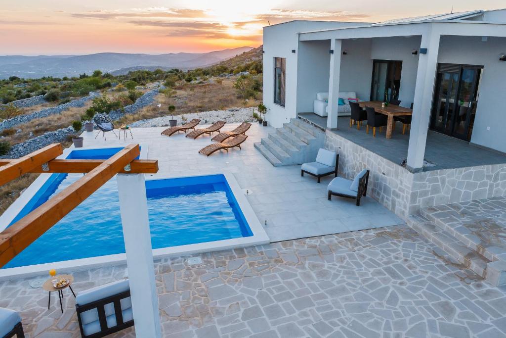 een villa met uitzicht op een huis met een zwembad bij Villa Zlatno Sunce in the hills near Trogir in Vrsine