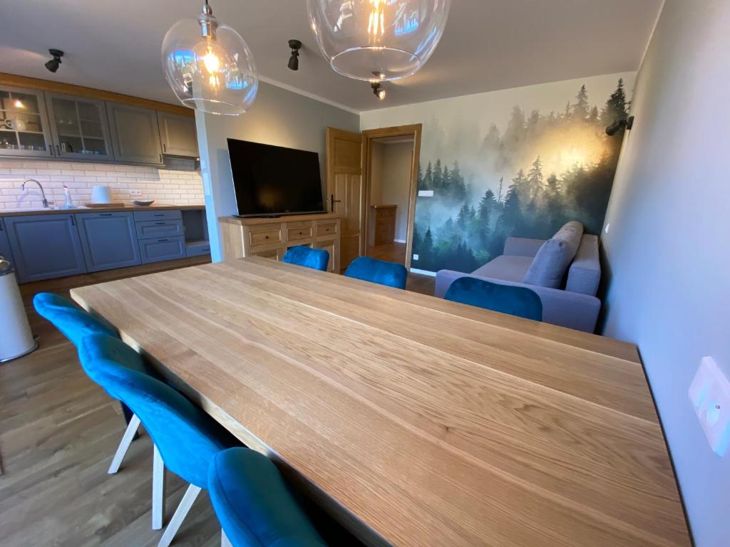 uma sala de jantar com uma mesa de madeira e cadeiras azuis em Apartament Zdrojowa z tarasem i ogrodem em Polańczyk