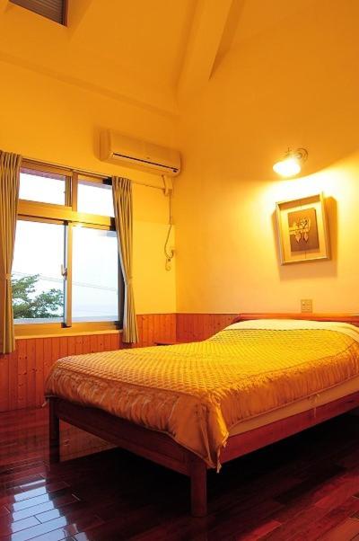 ein Schlafzimmer mit einem Bett und einem Fenster in der Unterkunft 千禧山莊民宿 in Fengbin