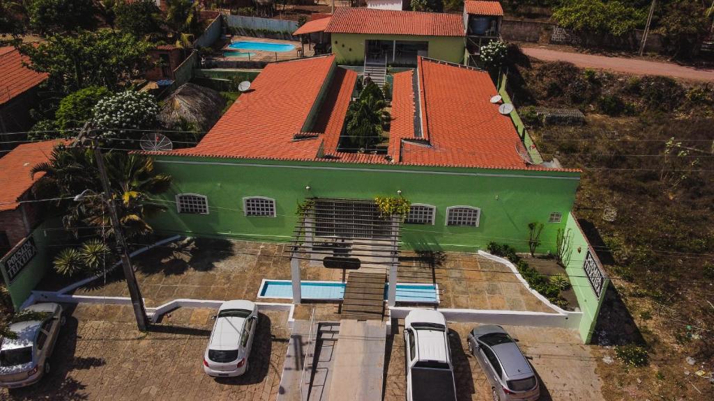 a green house with cars parked in front of it at POUSADA TEIXEIRA in Barreirinhas
