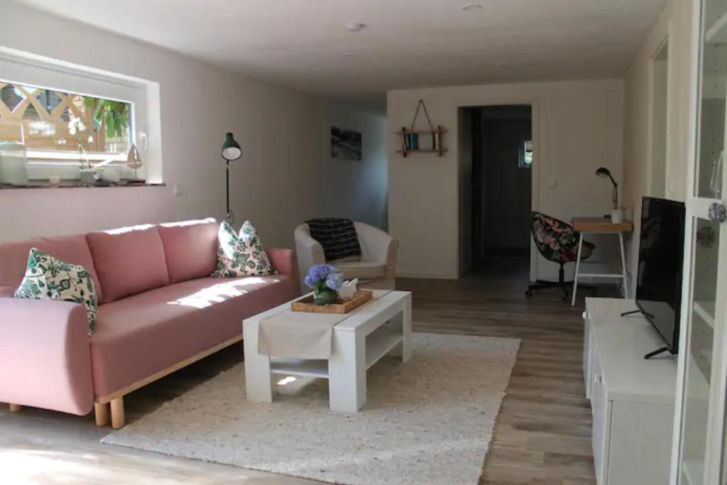 ein Wohnzimmer mit einem rosa Sofa und einem Tisch in der Unterkunft FeWoGeestland in Bremerhaven