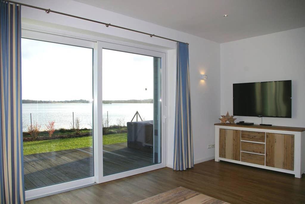 a living room with a sliding glass door with a television at FeWo Am See 15A in Klein Wittensee