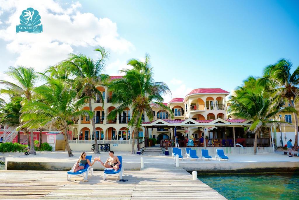 people sitting on beach chairs in front of a resort at SunBreeze Suites in San Pedro