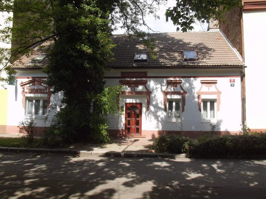 a white house with a red door on a street at Pension U akátu in Prague
