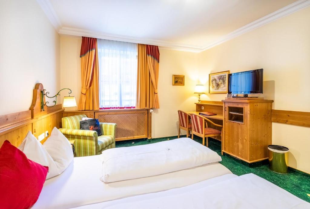 a hotel room with two beds and a desk at Hotel Zum Schwarzen Bären in Emmersdorf an der Donau