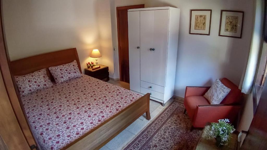 1 dormitorio con 1 cama y 1 silla roja en Suíte "Vale do Luar" - Capivari, en Campos do Jordão