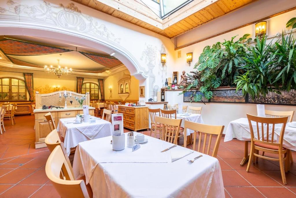 a restaurant with tables and chairs and plants at Hotel Zum Schwarzen Bären in Emmersdorf an der Donau