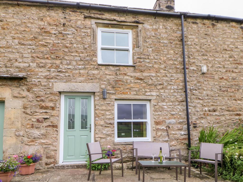 a stone building with a table and chairs in front of it at Margaret's Cottage in Feetham
