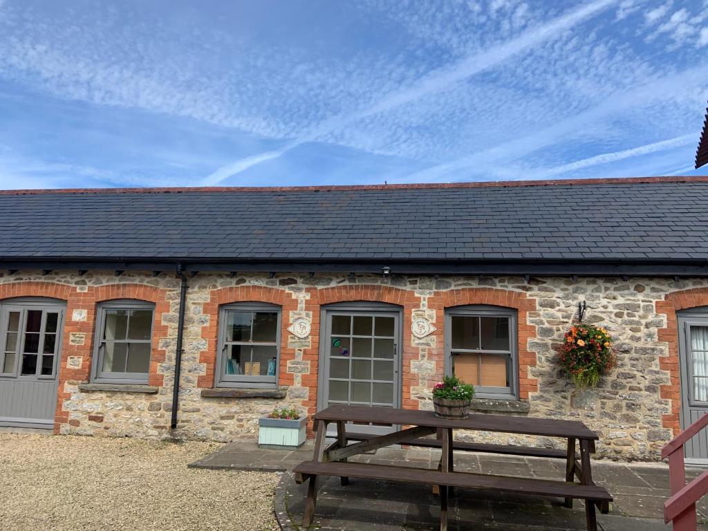 una casa de ladrillo con una mesa de picnic delante de ella en Kingfisher Cottage at Duffryn Mawr Cottages, en Hensol