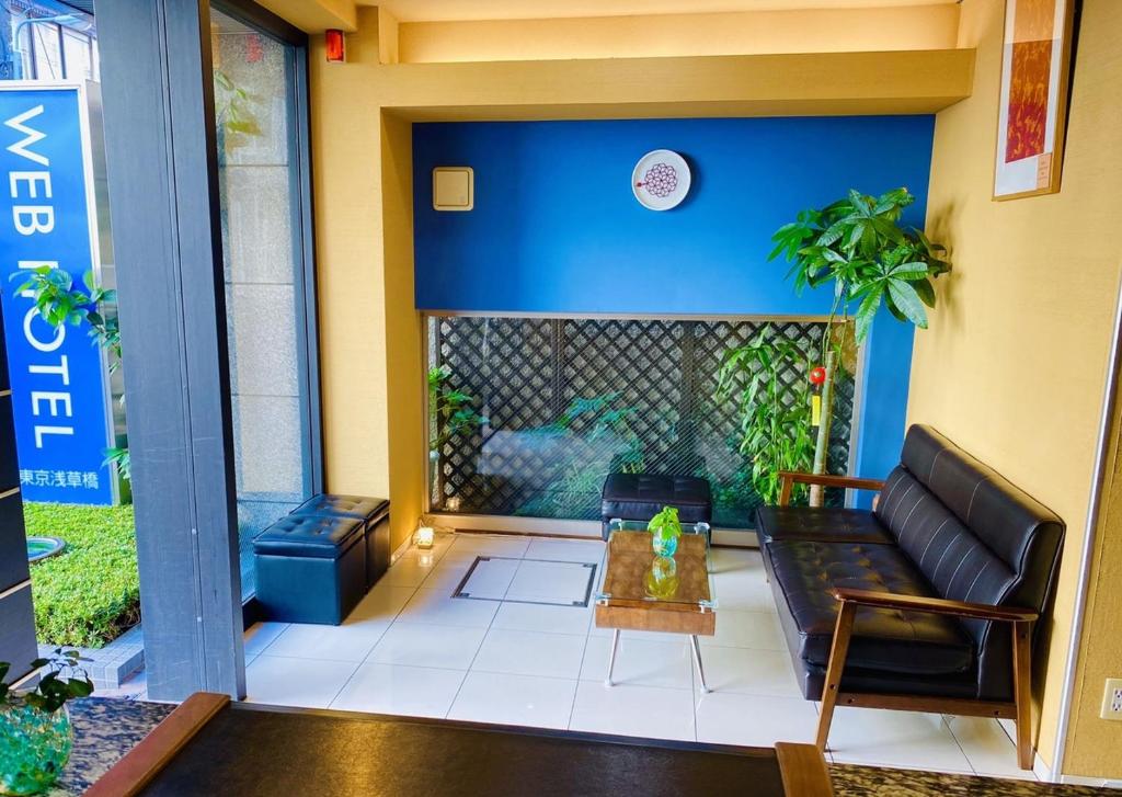 Web Hotel Tokyo Asakusabashi في طوكيو: غرفة معيشة مع أريكة والجدار الأزرق