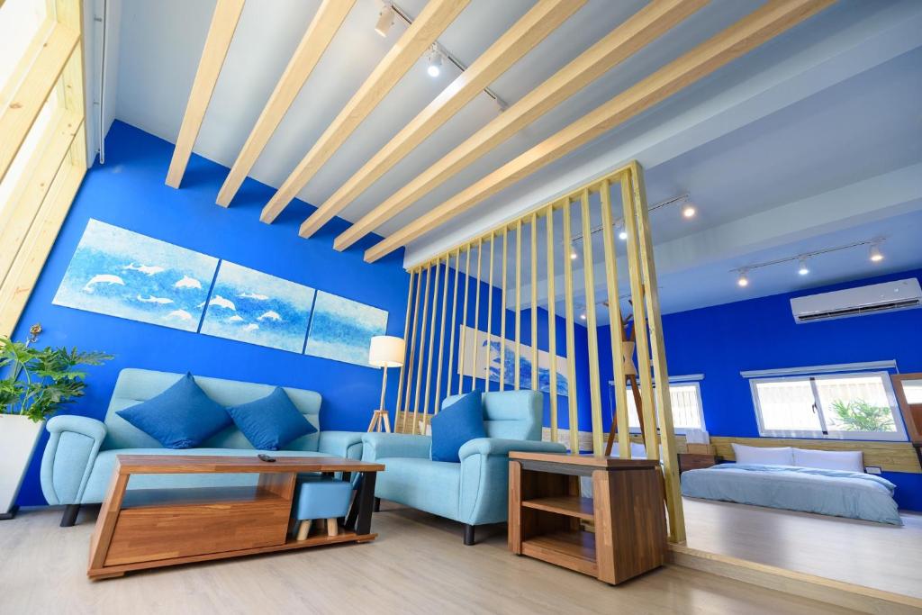 ein Wohnzimmer mit blauen Wänden und einem blauen Sofa in der Unterkunft 夏天民宿 in Magong