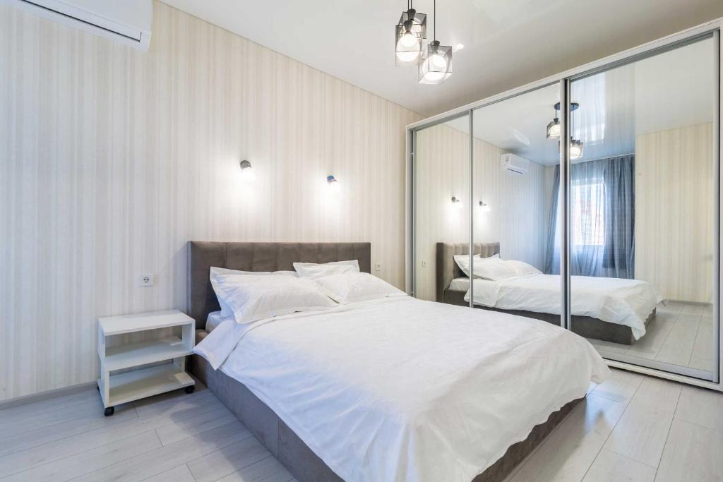 1 dormitorio con 1 cama blanca grande y espejo en City Center 2-bedroom apartment, en Dnipro