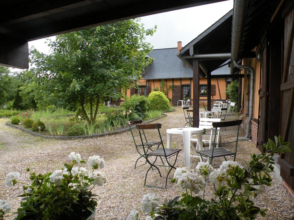 a patio with chairs and a table and flowers at Les Granges Du Bout De La Ville in Montville