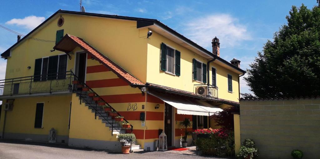 a yellow and red house with a staircase on it at B&B Country House Crema in Crema