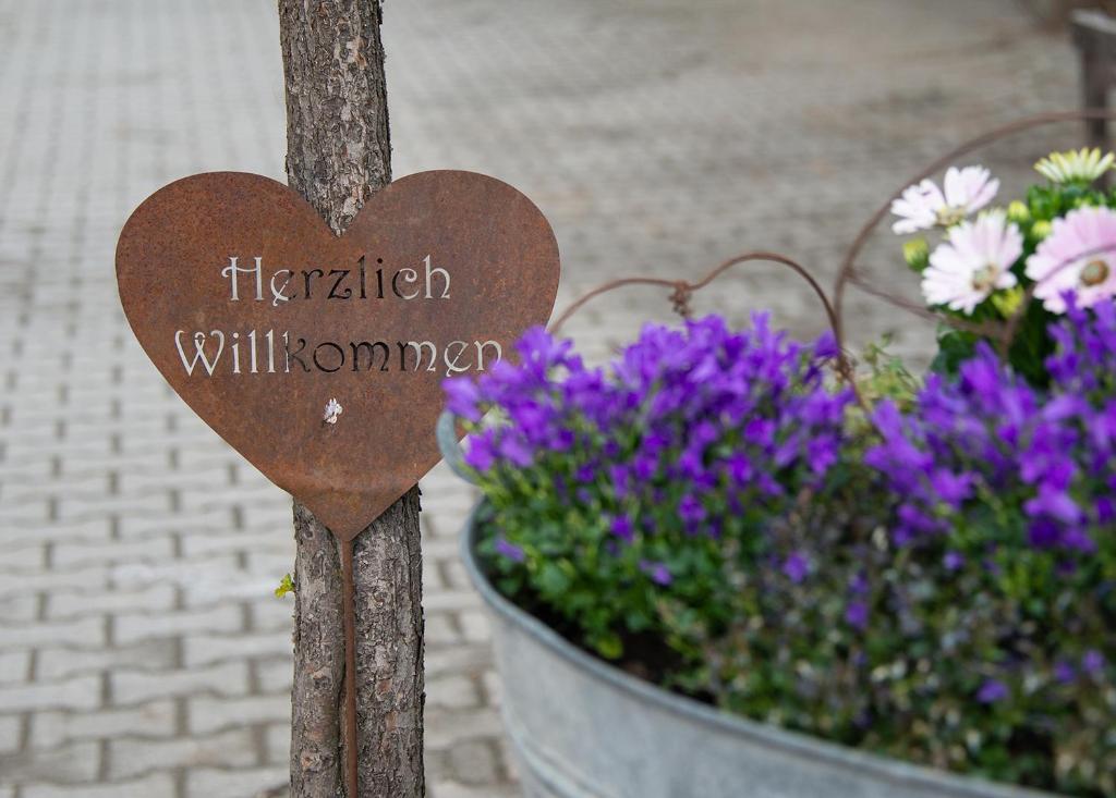 un signo cardíaco de madera frente a una maceta de flores en Gut Tausendbachl, en Regen