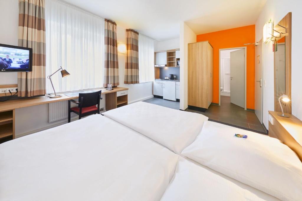 デュッセルドルフにあるタウンハウス デュッセルドルフのベッドとデスクが備わるホテルルームです。