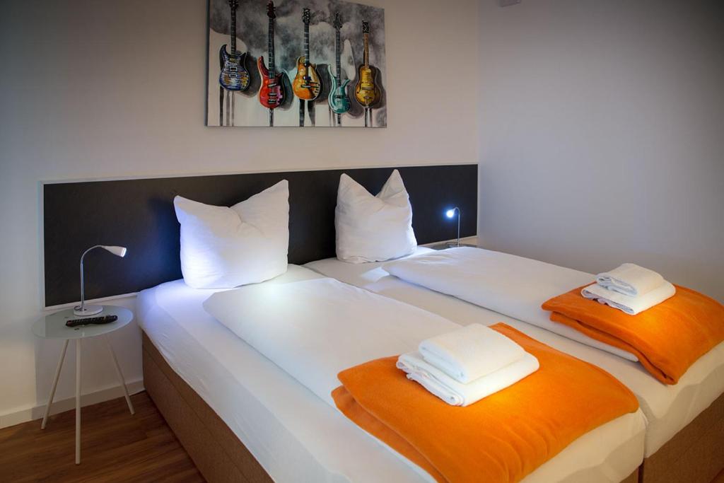 2 Betten mit orangefarbenen und weißen Kissen in einem Zimmer in der Unterkunft H&H Apartment im Greifswald Eldena Nr19-Jonas mit Terrasse in Greifswald