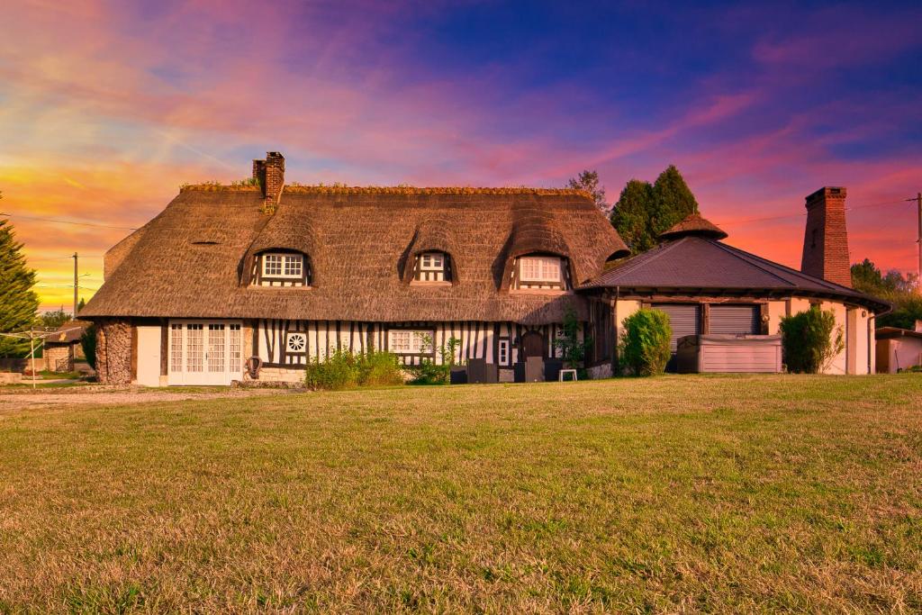 una casa grande con un campo de hierba delante de ella en La Régissière, en Vatteville