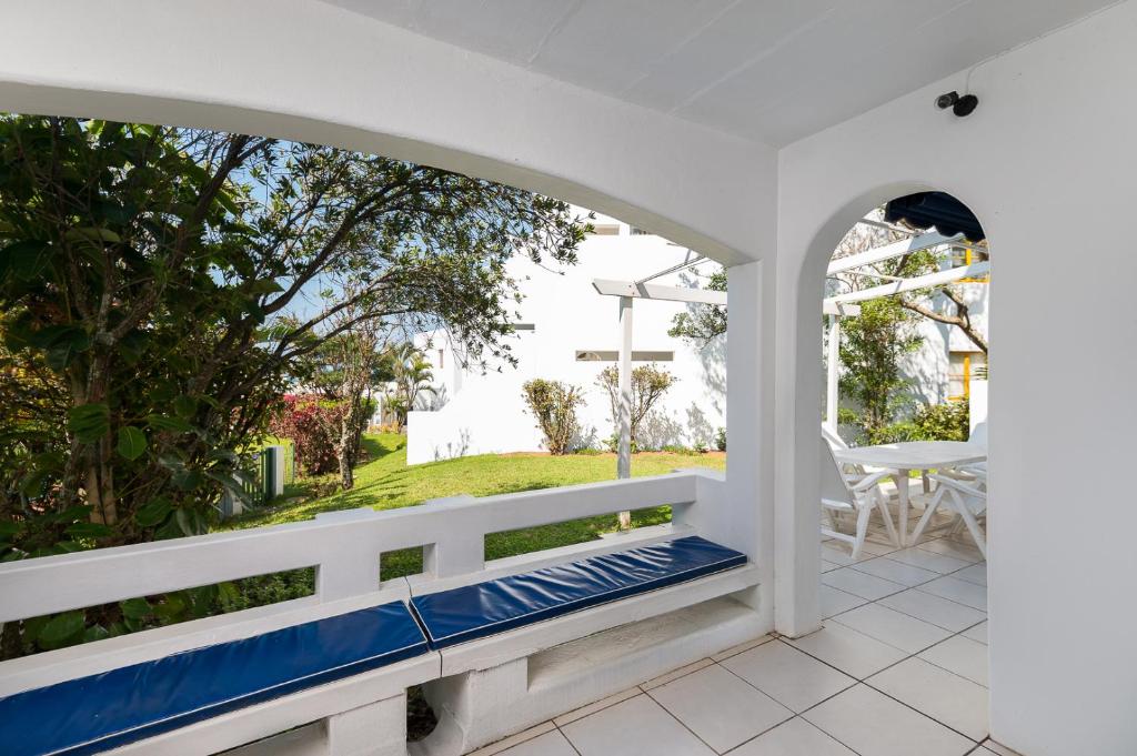 a white porch with an archway and a bench at Santorini - Akrotiri 3 in Ballito