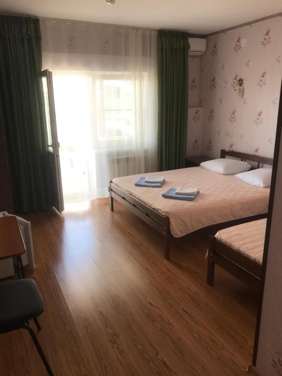 a bedroom with two beds and a window with green curtains at Guest house Fortuna in Adler