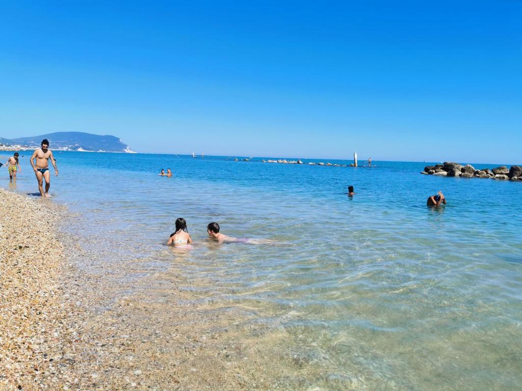 um grupo de pessoas na água em uma praia em A due passi dal mare em Porto Recanati