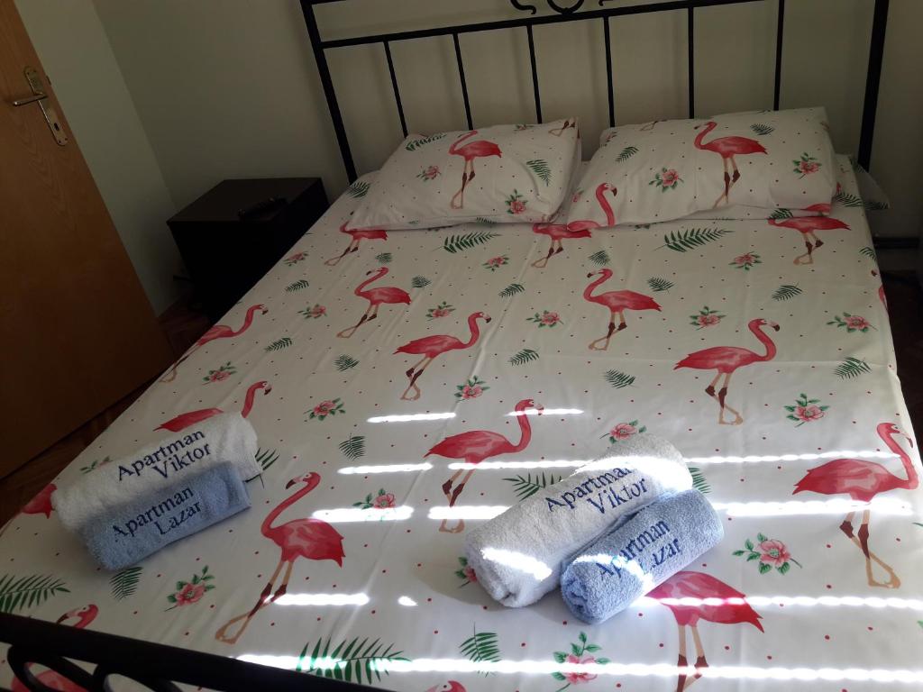 ein Bett mit rosa Flamingos drauf mit Handtüchern drauf in der Unterkunft Apartman LAZAR I VIKTOR in Vrnjačka Banja