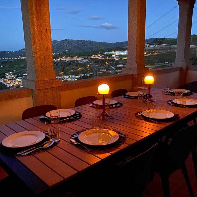a wooden table with plates and lights on top of it at Quinta da Mesquinhata in Lamego