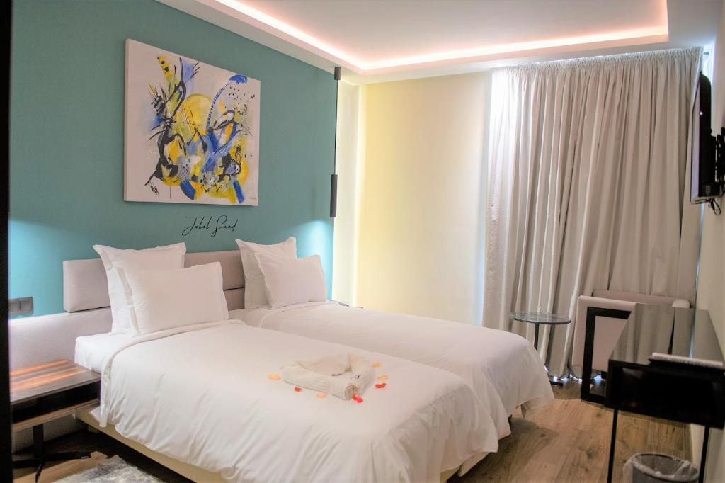 una camera da letto con un letto bianco e un animale di peluche di NJ Hotel Rabat a Rabat