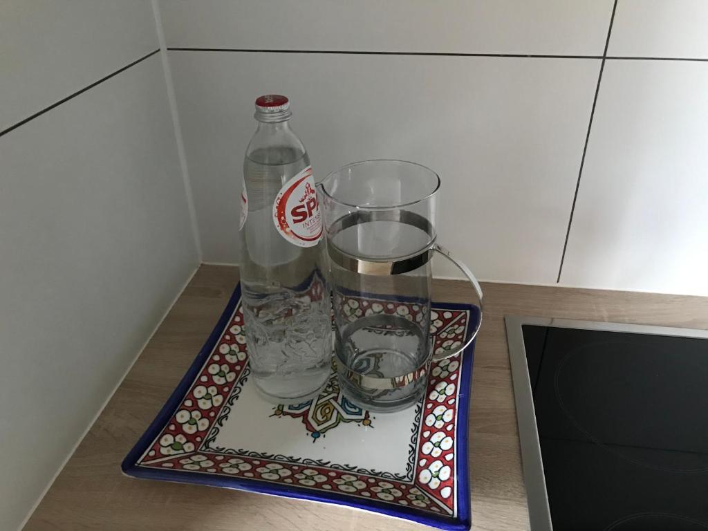 a tray with two glasses and a bottle of water at Lumineux appartement in Louvain-la-Neuve