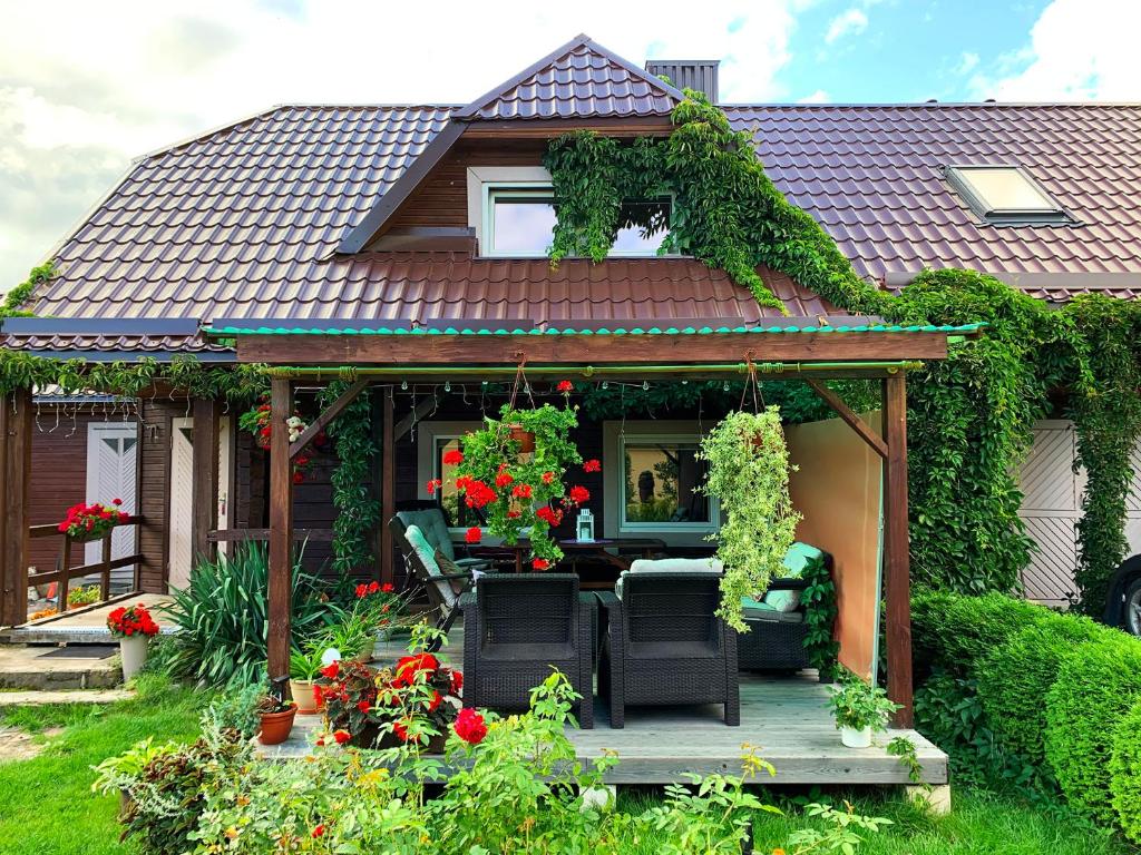 a house with a porch with two chairs and flowers at Prie Ąžuolo in Zarasai