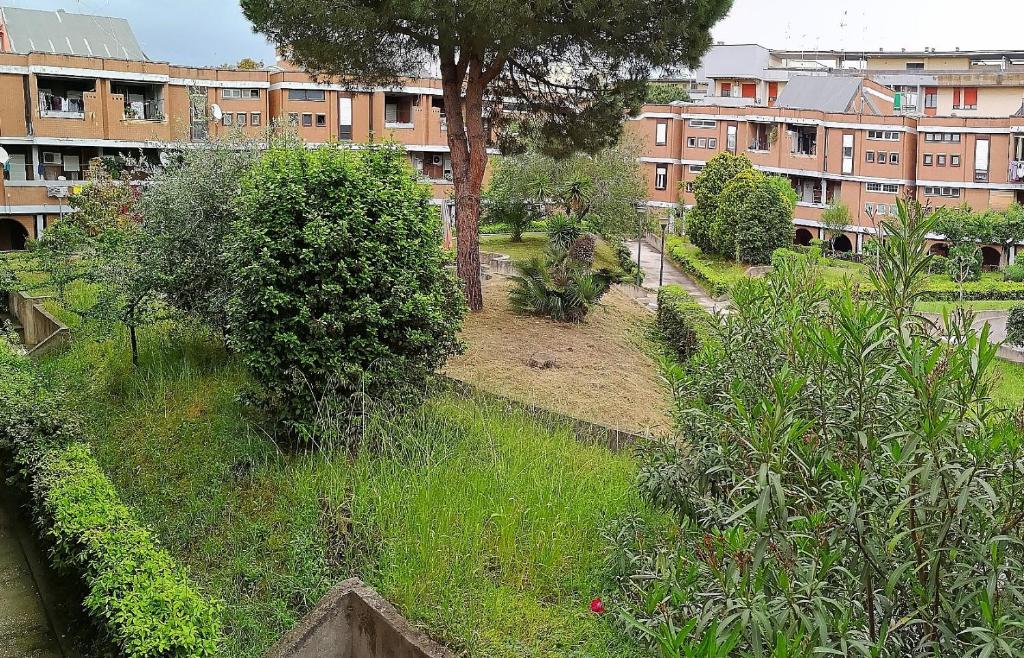 un jardín con arbustos y árboles y un edificio en Casa di Adele, en Anzio