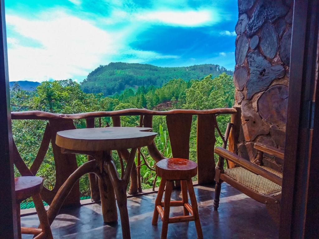 a table and chairs on a balcony with a view of mountains at CHILL Wood ELLA in Ella