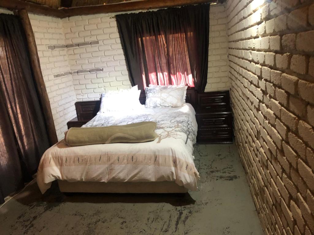 1 dormitorio con 1 cama en una pared de ladrillo en Motlopi Game Farm, en Thabazimbi