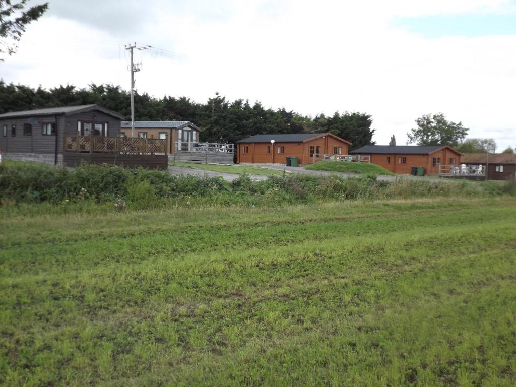 a field of grass with houses in the background at Avonvale Holiday Lodges in Evesham