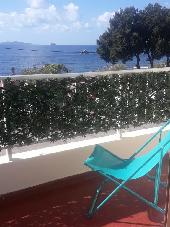 une chaise bleue assise sur un balcon donnant sur l'océan dans l'établissement BRILOC Appartement Route des îles Sanguinaires, à Ajaccio