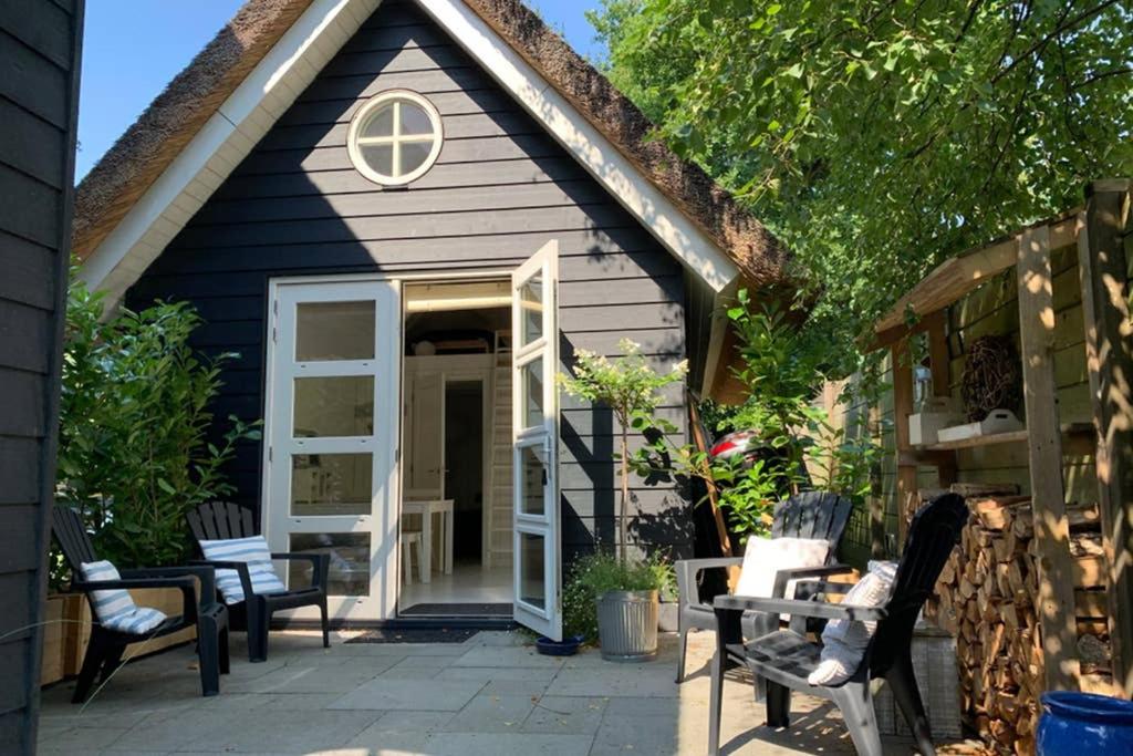 een klein huis met stoelen en een patio bij Bergen, Huisje dat ademt zee en vakantie... in Bergen