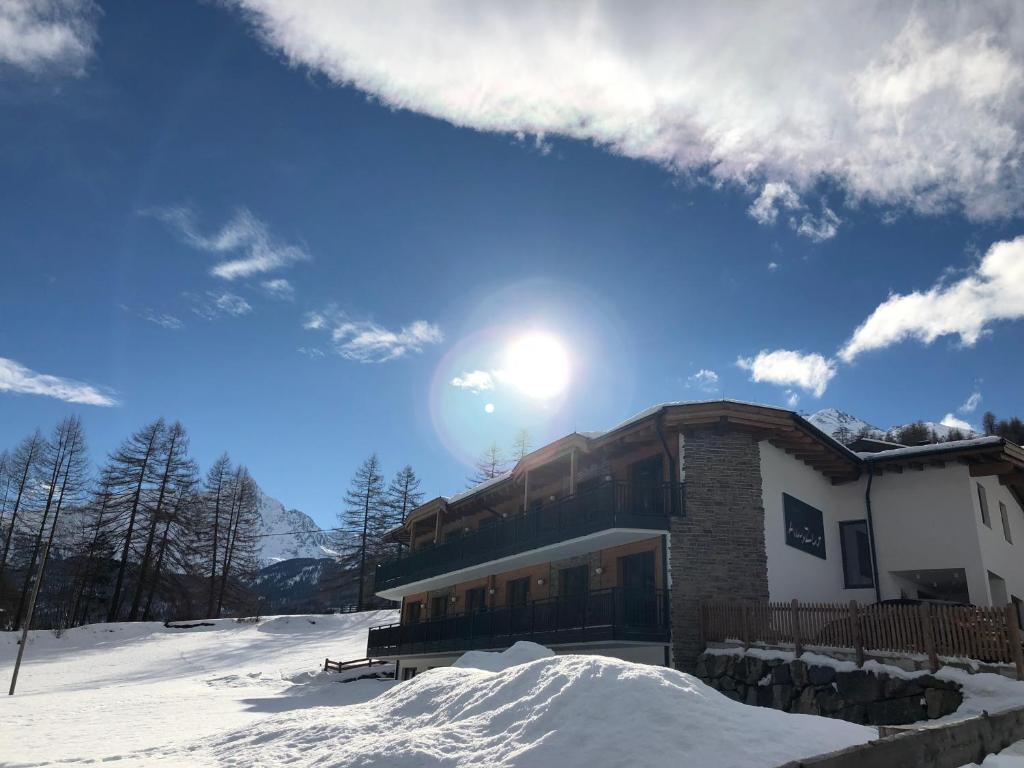 a house in the snow with the sun in the sky at Apart Auszeit in Sölden