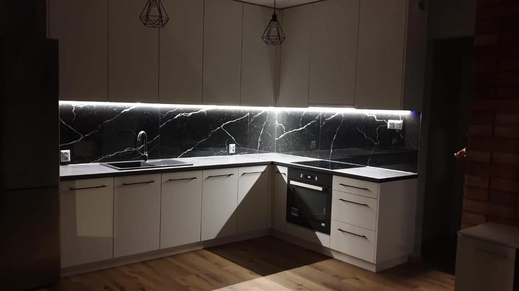 a kitchen with white cabinets and black marble counter tops at Apartament Panoramiczna in Kielce