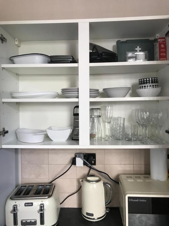 a kitchen with white shelves with dishes and a toaster at Richmond Luxury flat Fabulous location in Southend-on-Sea