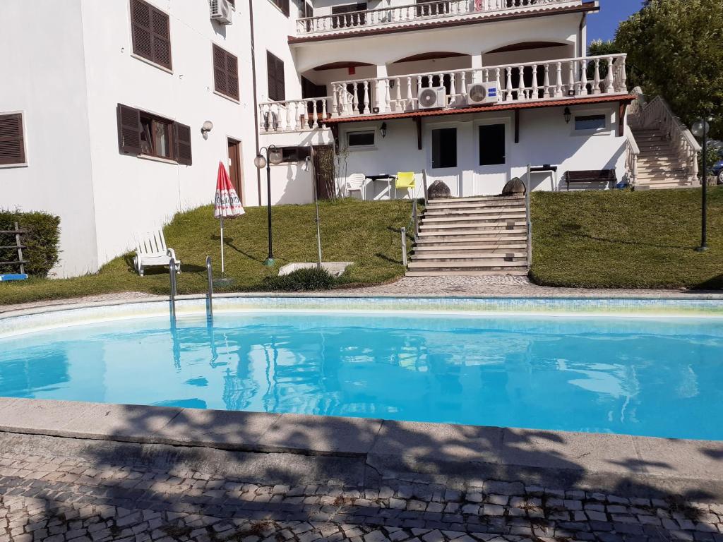 a house with a swimming pool in front of a building at Jantesta Guest House in Coimbra