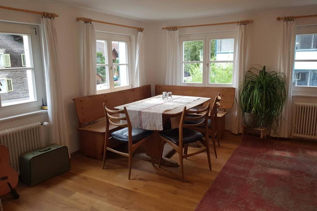 a dining room with a table and chairs and windows at Ferienwohnung am Hatler Brunnen in Dornbirn