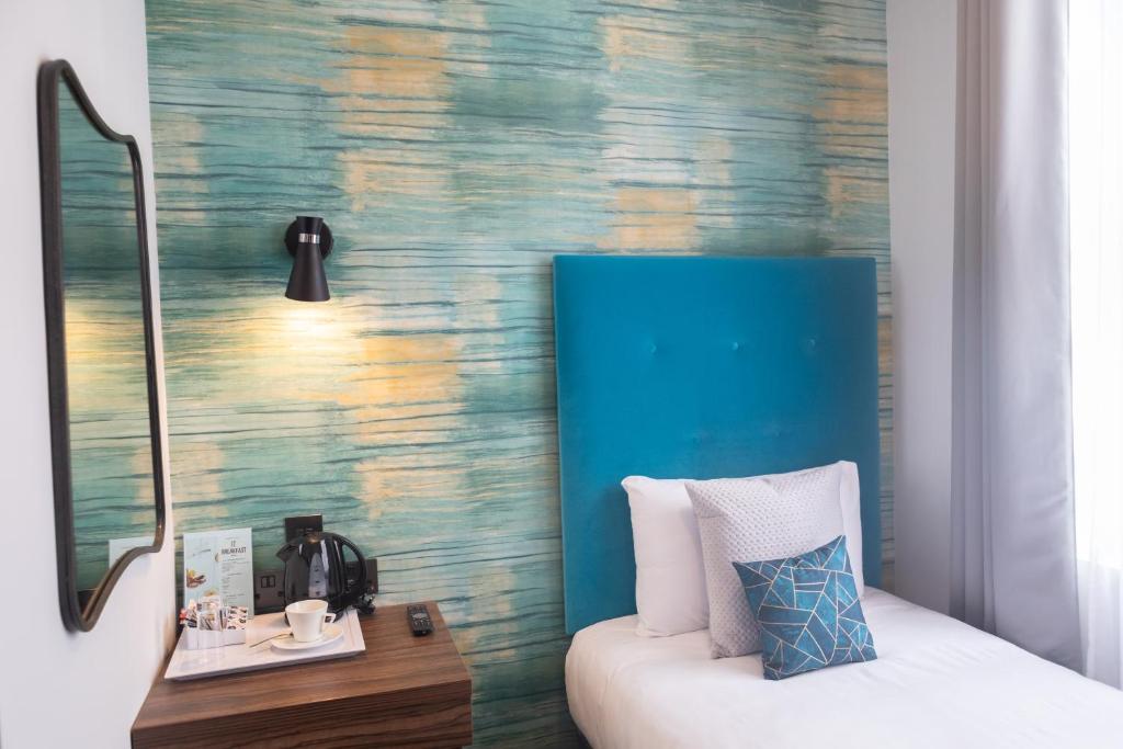 Habitación con cama y pared azul en Paddington Park Hotel, en Londres