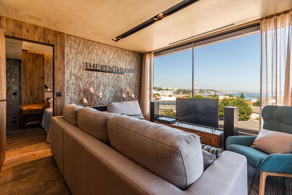 een woonkamer met een bank en een groot raam bij THE miniPENTHOUSE terrace & SPA in Paço de Arcos