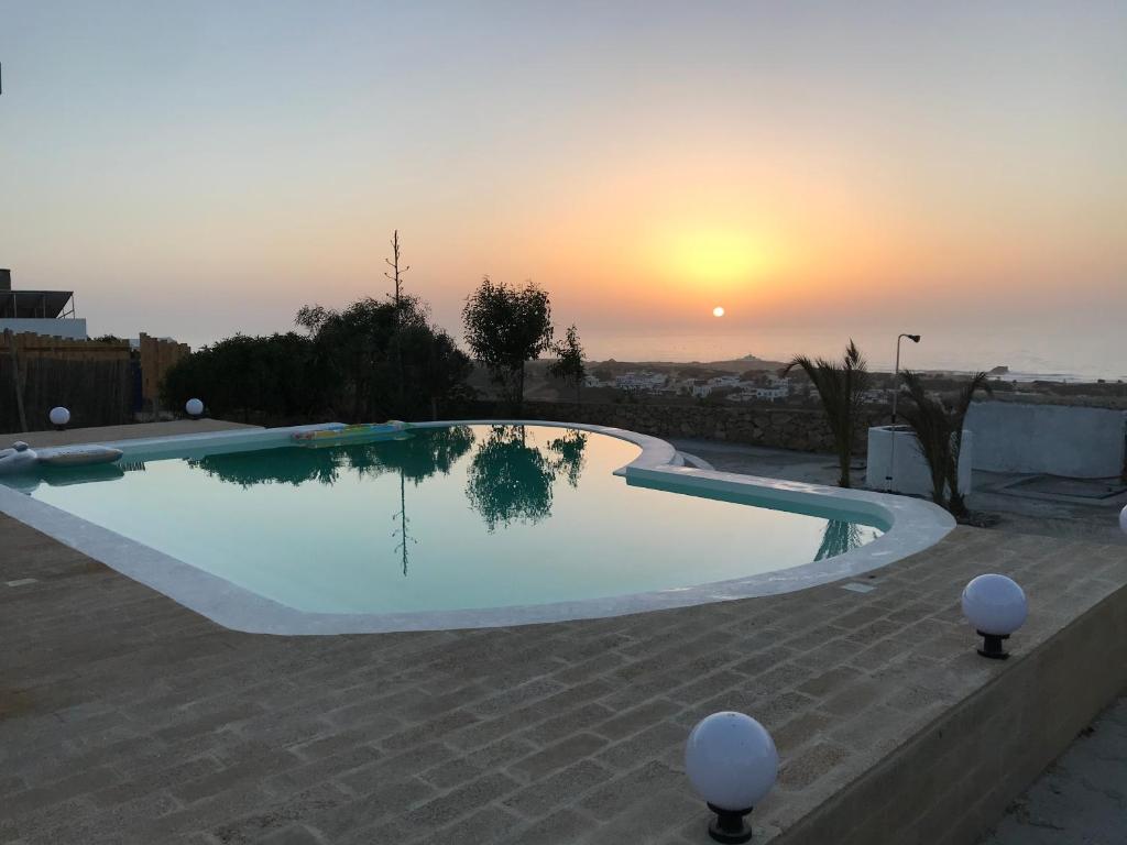 a large swimming pool with a sunset in the background at Les oliviers in Oualidia
