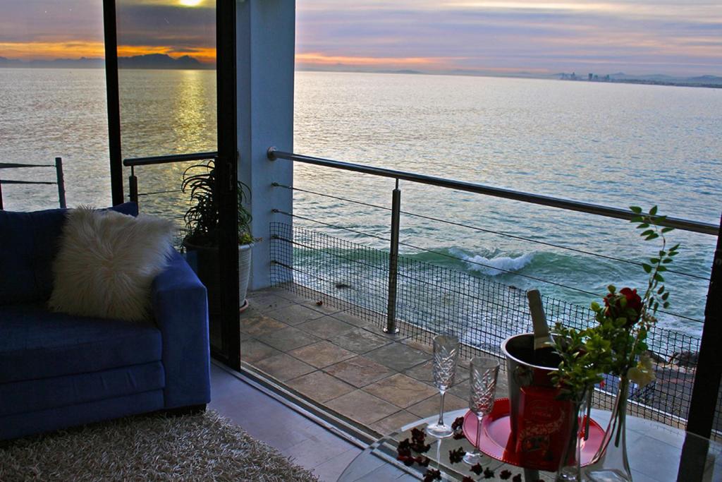 a living room with a balcony overlooking the ocean at 185 on BEACH Boutique Suites in Gordonʼs Bay